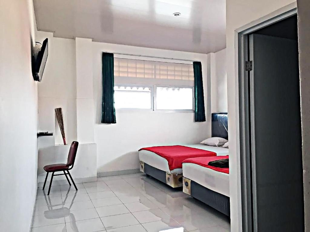 日惹Mitra Hotel的卧室配有床、椅子和窗户。