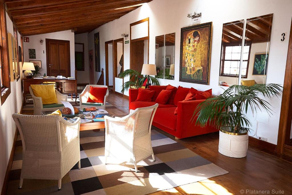 伊科德洛斯维诺斯Platanera Suites的客厅配有红色的沙发和椅子