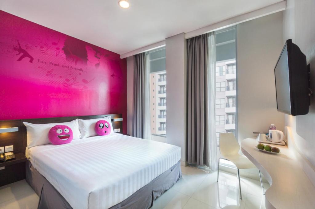 雅加达雅加达珐维盖特斯波特酒店的一间卧室设有粉红色的墙壁和一张带Hello Kitty枕头的床。