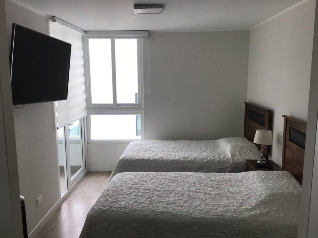 利马Moderno y funcional departamento Miraflorino的一间卧室配有两张床和一台平面电视