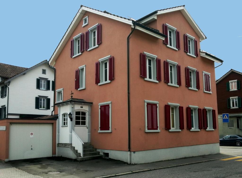 戈绍Ferienwohnungen im Fürstenland的红色的建筑,有红色的门和车库