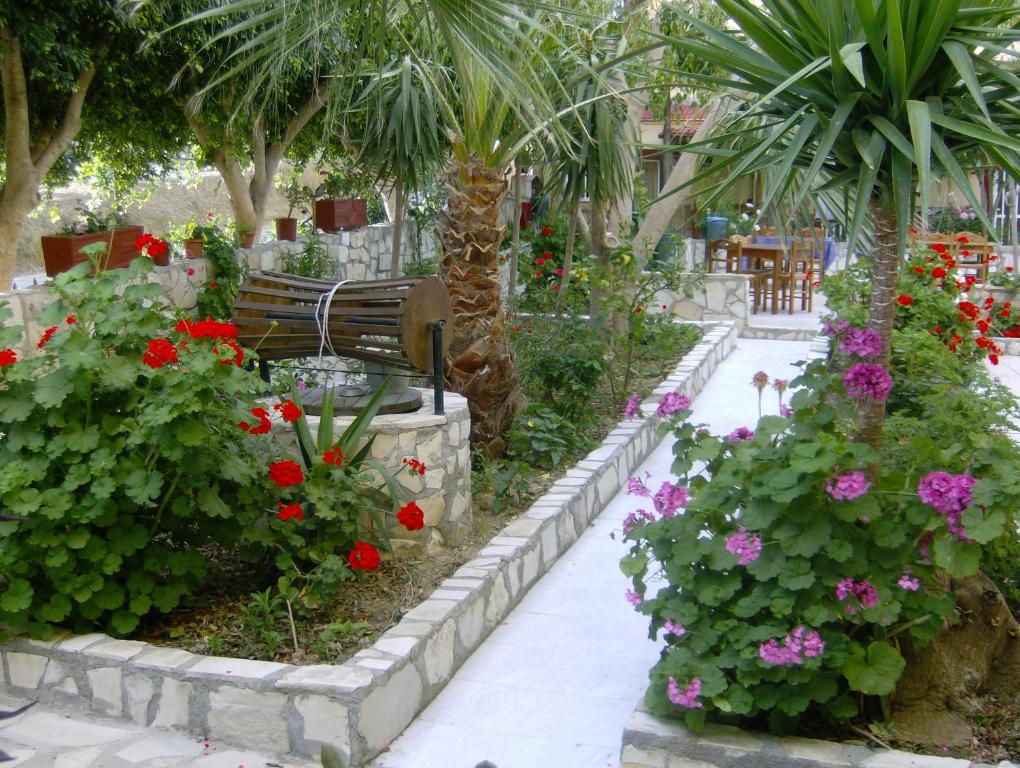 Sívas科斯塔斯 - 波皮别墅旅馆的种有鲜花、长凳和棕榈树的花园