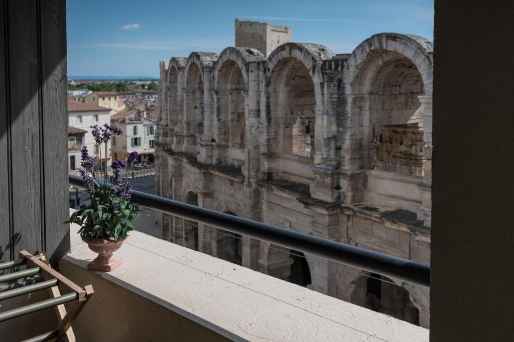 阿尔勒Studio avec balcon donnant sur les Arènes d’Arles的花瓶坐在建筑物的阳台上