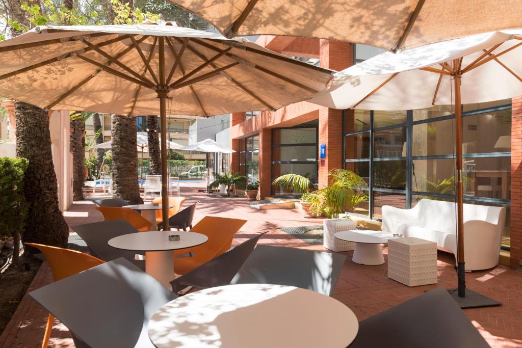 贝尼多姆 帕尔梅拉酒店的一个带桌椅和遮阳伞的庭院