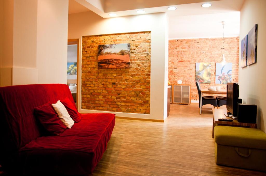 波兹南23号公寓 的客厅设有红色沙发和砖墙