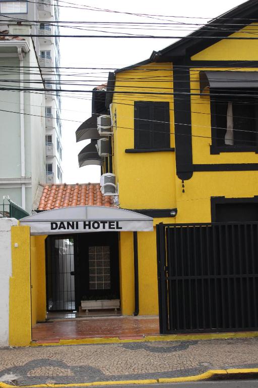 坎皮纳斯DANI HOTEL的黄色的建筑,上面标有读取酒店时用的标志