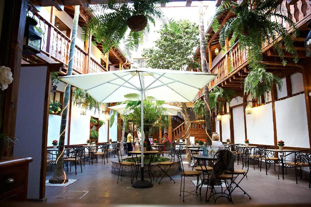 伊科德洛斯维诺斯埃姆布勒玛提卡圣奥古斯丁酒店的一个带桌椅和遮阳伞的庭院