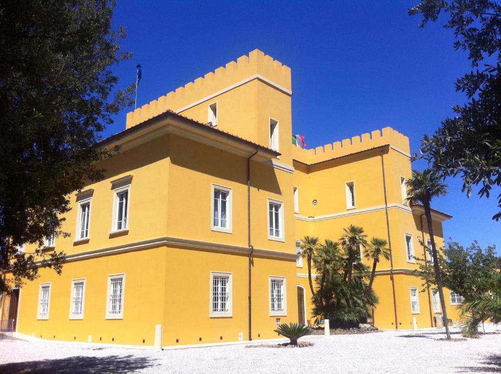 瓦达Villa Graziani的一座黄色的大建筑,前面有树木