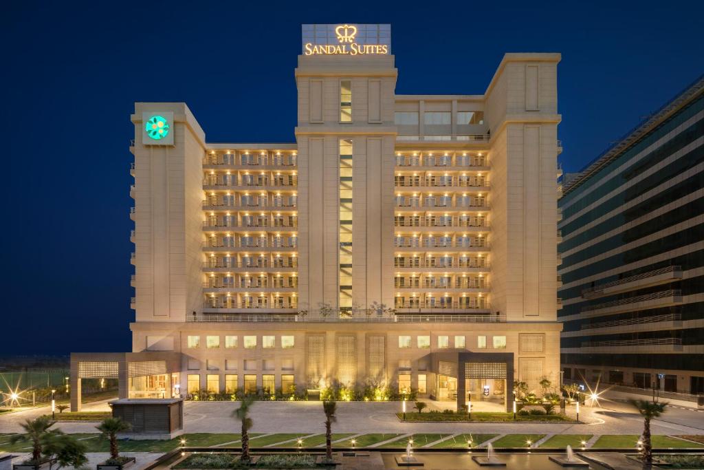 诺伊达Sandal Suites by Lemon Tree Hotels的一座酒店大楼,晚上有钟楼