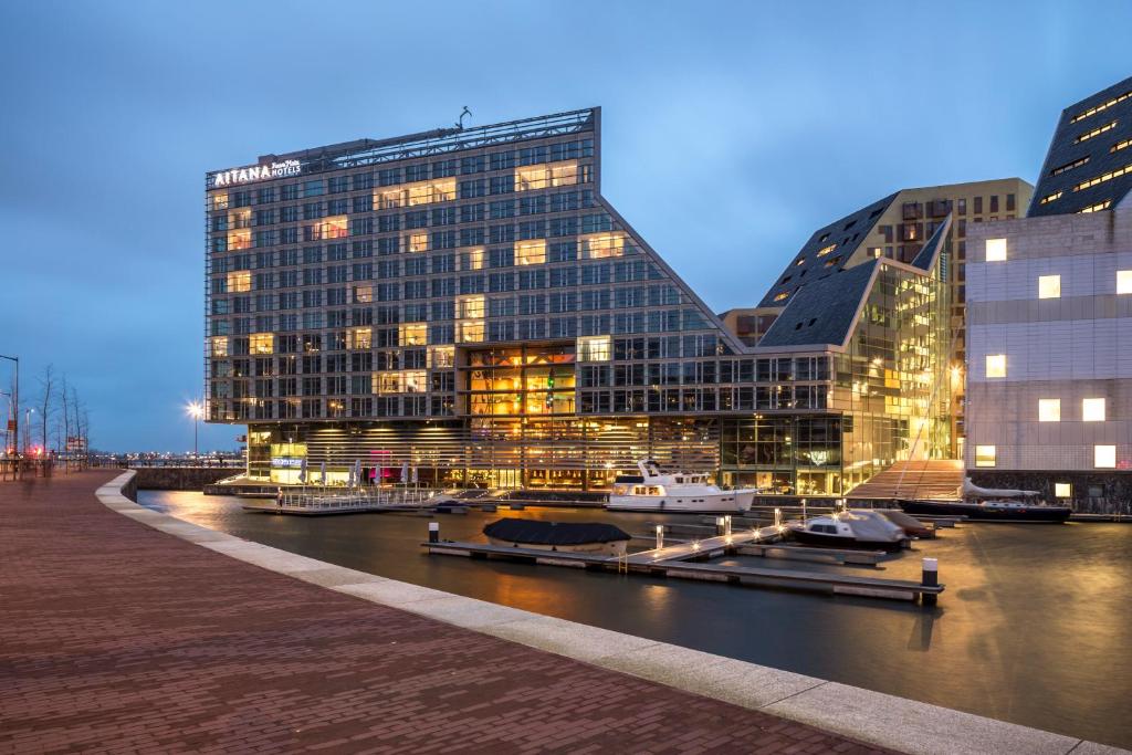 阿姆斯特丹艾塔娜室友酒店的一座大建筑,毗邻一条河,有建筑物