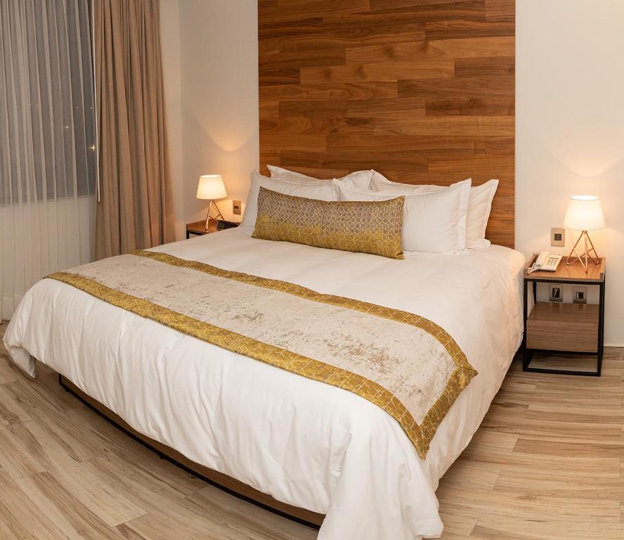 Santa Cruz TecamacHotel Verticca的卧室配有一张白色大床和木制床头板