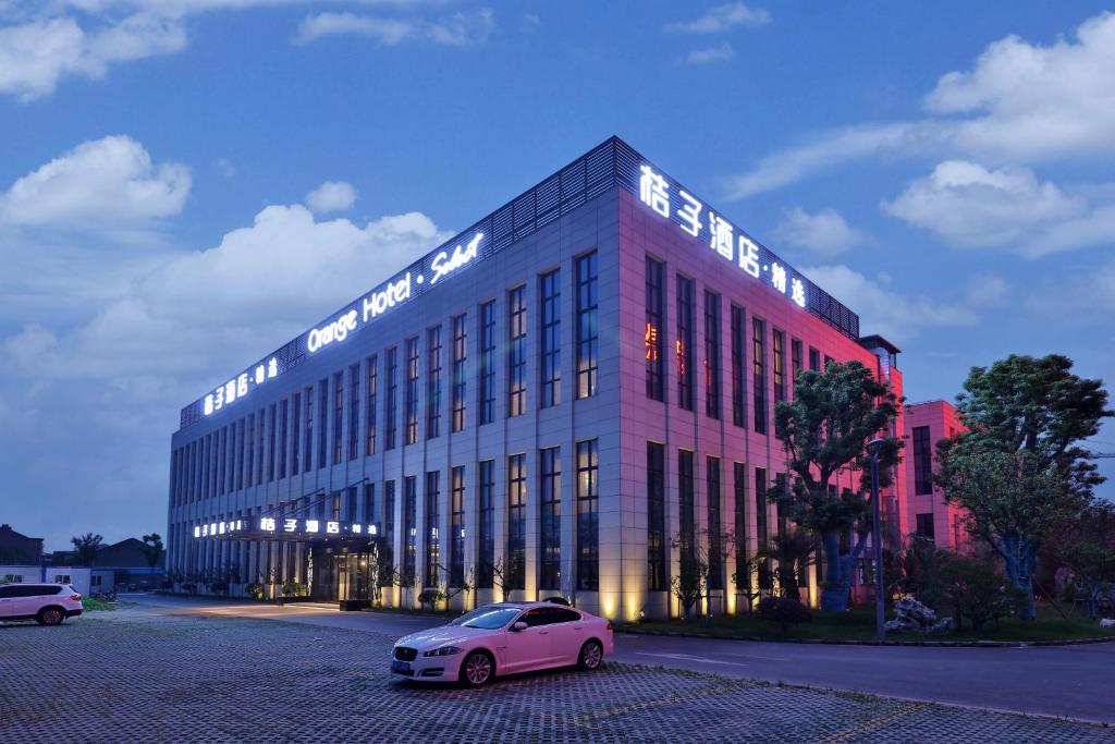 上海桔子酒店(上海浦东机场店)酒店提供浦东机场免费接送服务的停在大楼前的粉红色汽车