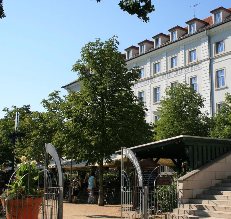 德累斯顿Hotel am Waldschlösschen - Brauhaus的前面有一棵树的白色大建筑
