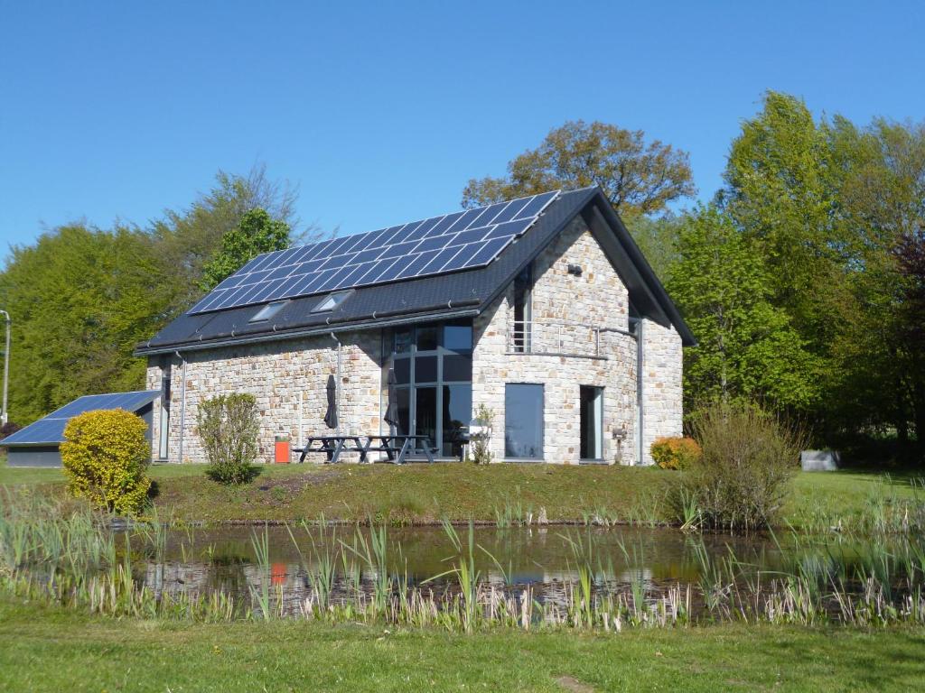 奥维法特Oxygen House, Holiday and Team building的池塘旁的屋顶上设有太阳能电池板的谷仓