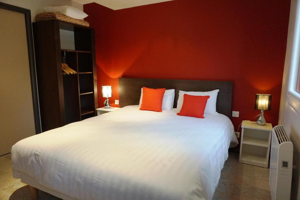 第戎科隆比尔公园餐厅酒店的卧室配有一张白色大床和红色的墙壁