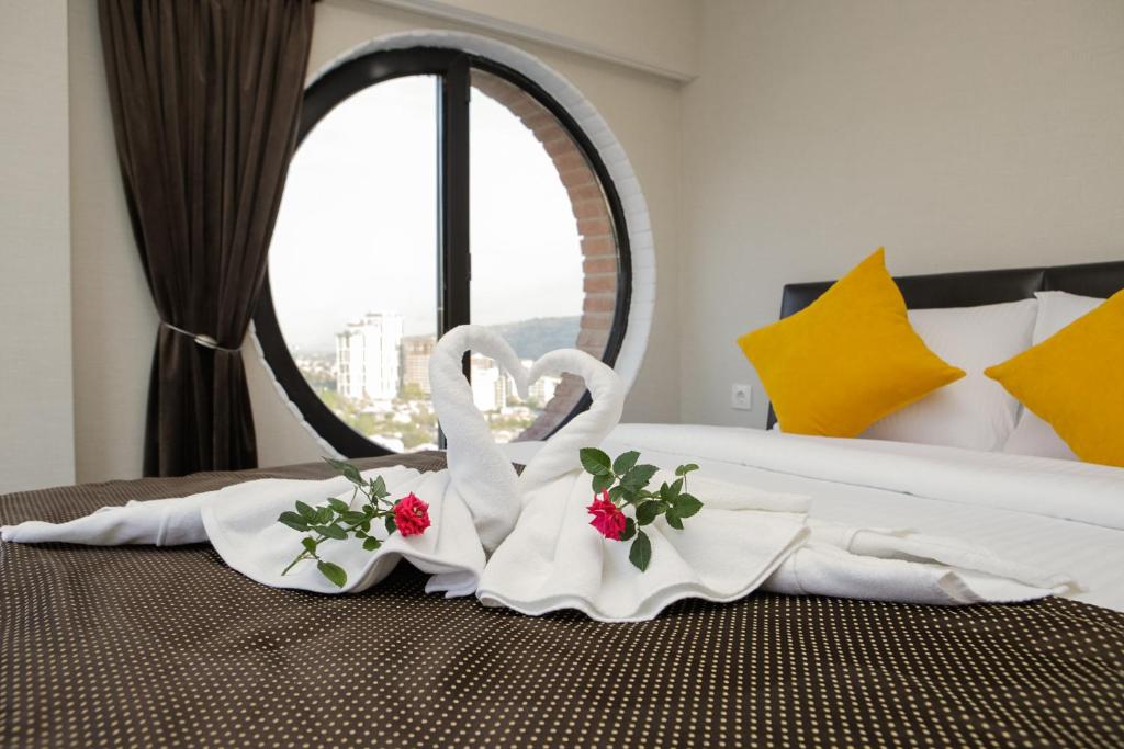 第比利斯Boutique Hotel的窗前床边的两条天鹅毛巾