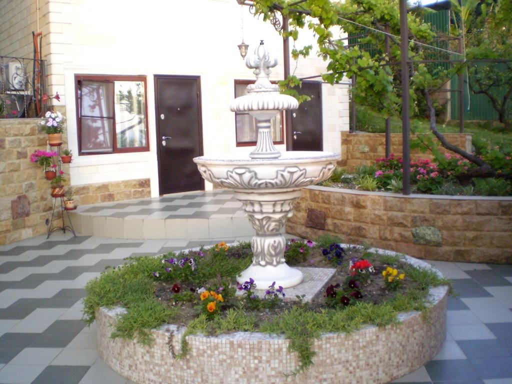 桑德雷什Гостевой дом Барс Абхазия的花团锦簇的庭院中央的喷泉