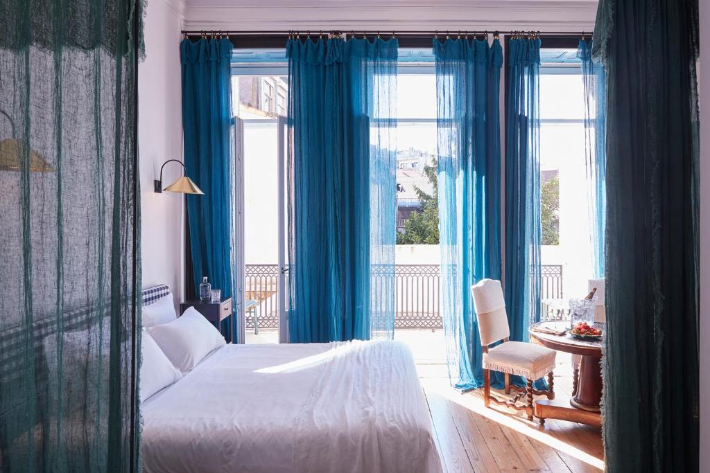 波尔图Cocorico Luxury House - Porto的一间卧室配有蓝色窗帘和一张床,并设有一个阳台