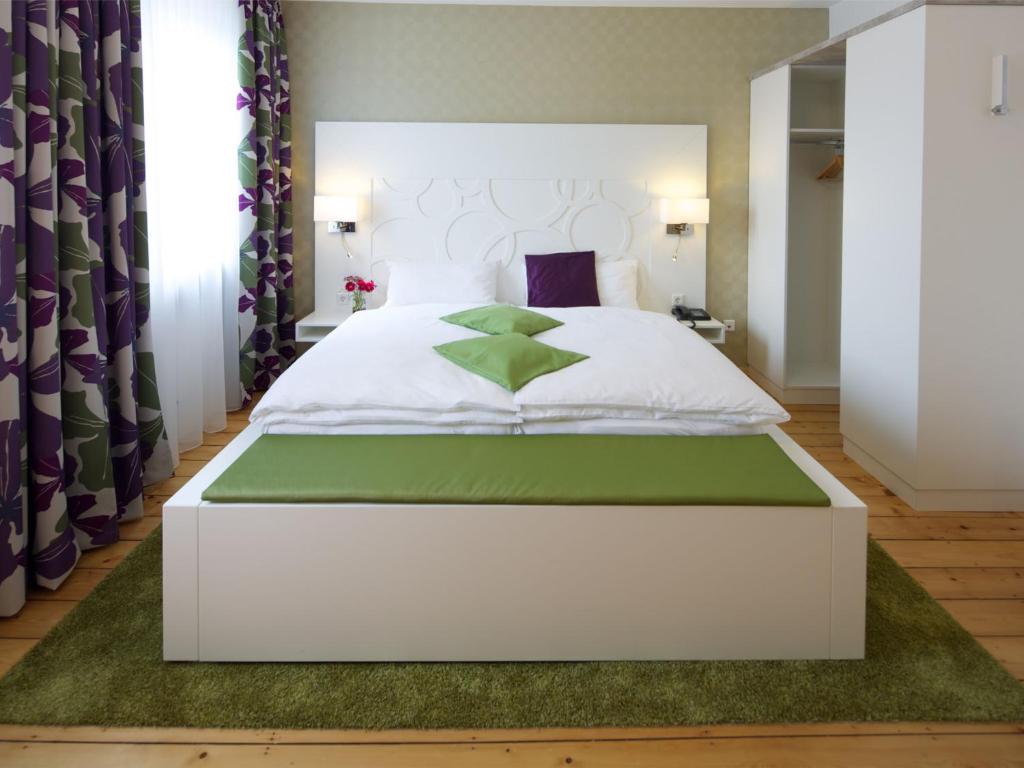 洛尔施Hotel Karolinger Hof的卧室配有白色床和绿色地毯