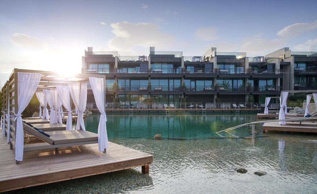 拉齐塞Quellenhof Luxury Resort Lazise的水面上带椅子的建筑