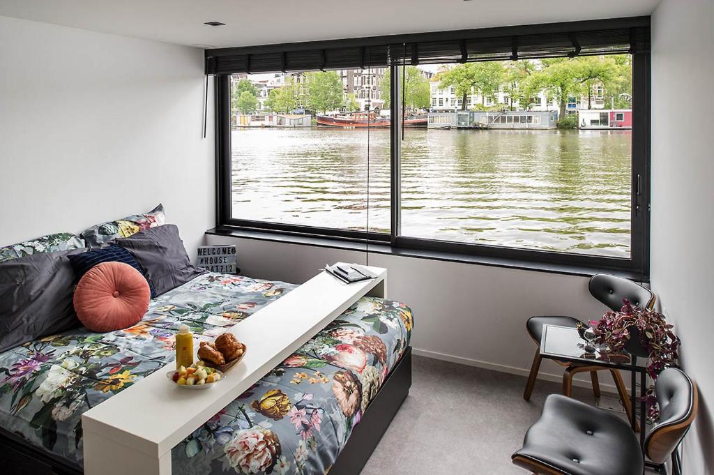 阿姆斯特丹Houseboat Amsterdam - Room with a view的卧室设有河景窗户。