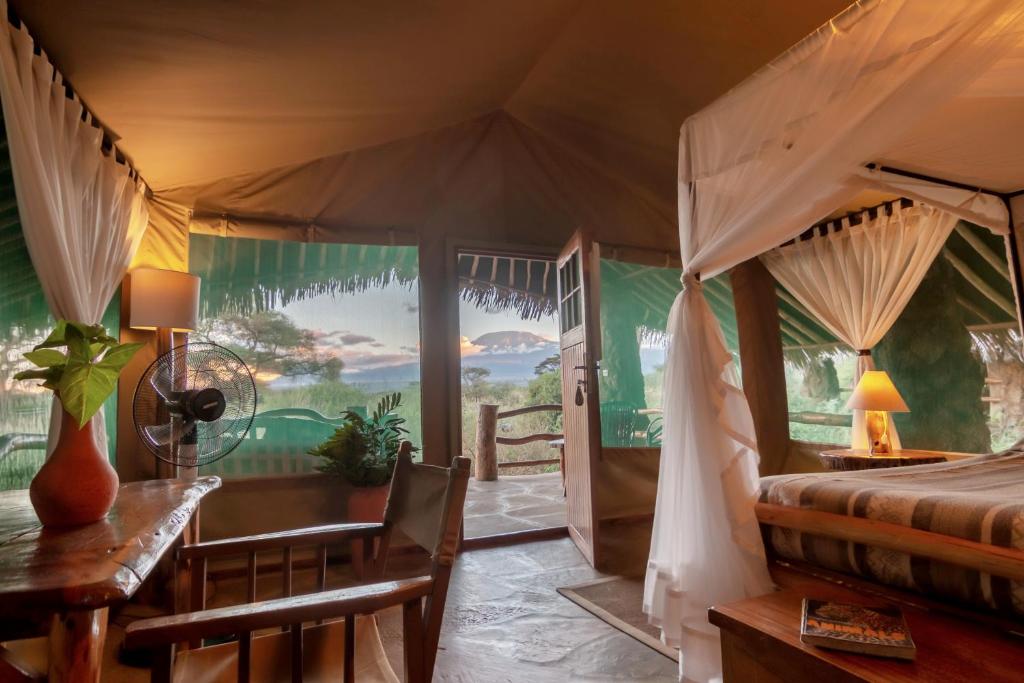 安博塞利基博狩猎帐篷营地的一间卧室配有一张床、一张桌子和一张桌子