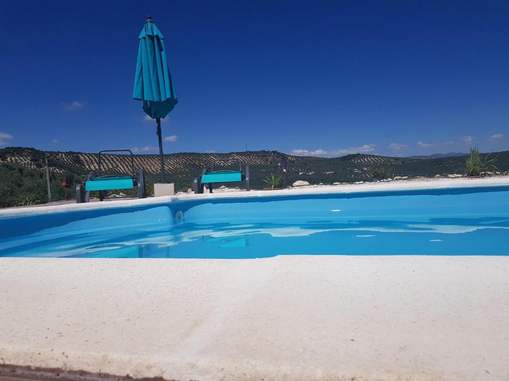 伊斯纳哈尔Cortijo de la Cruz的蓝色的游泳池,带蓝色的伞