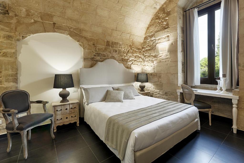 拉古萨Itria Palace的一间卧室配有一张床、两把椅子和一个窗户