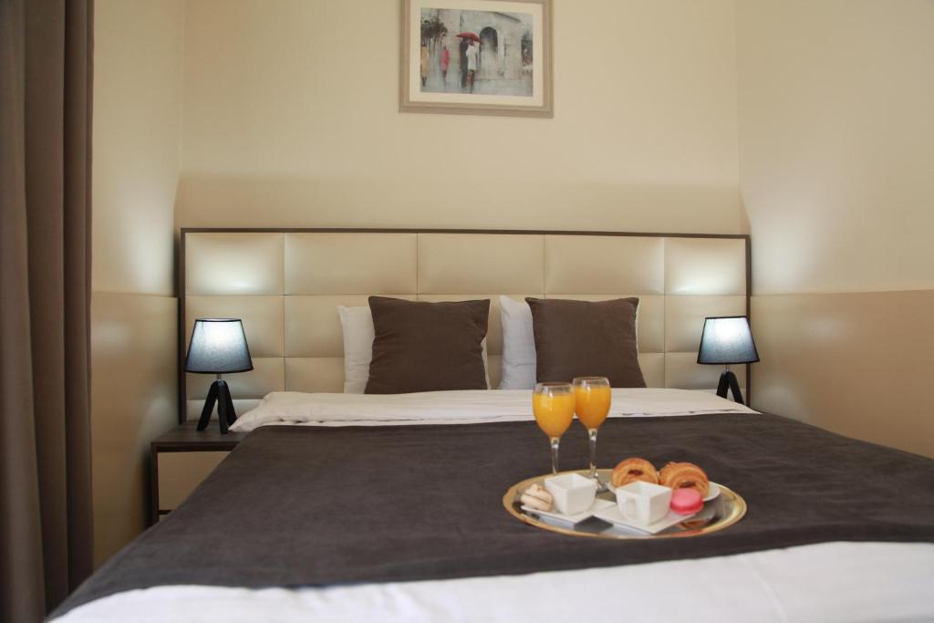 第比利斯里约酒店的一张带食物托盘和两杯酒的睡床