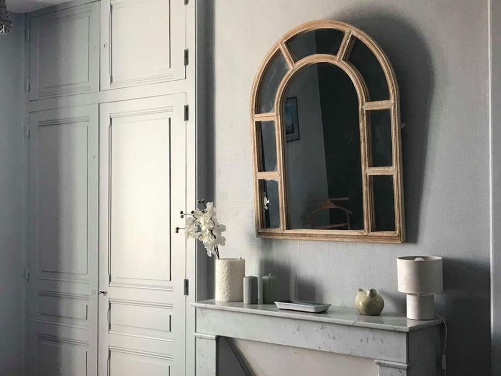 圣莱奥纳尔德诺布拉Le Compostelle Chic, Charme, Confort, Cocooning 80 m²的一面镜子坐在壁炉旁的墙上