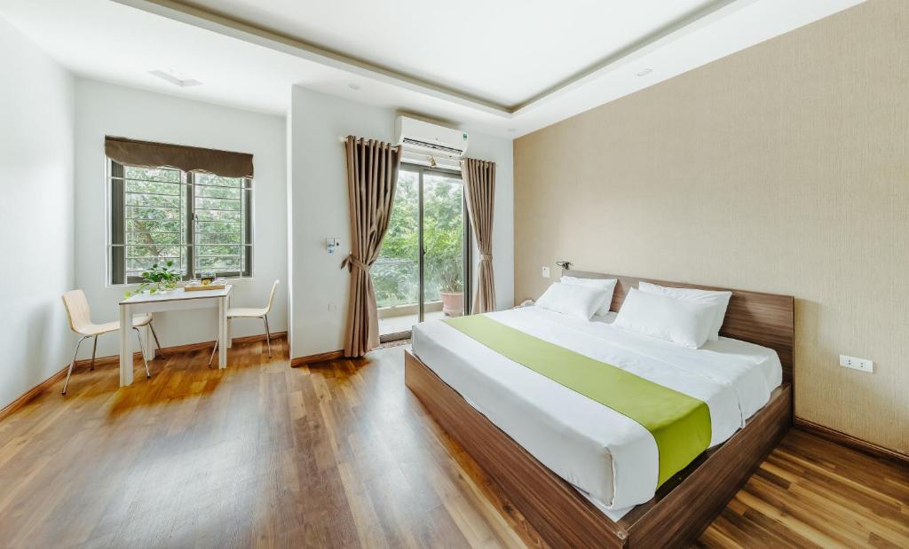 北宁Hana 1 Apartment & Hotel Bac Ninh的一间卧室配有一张大床、一张书桌和一个窗户。