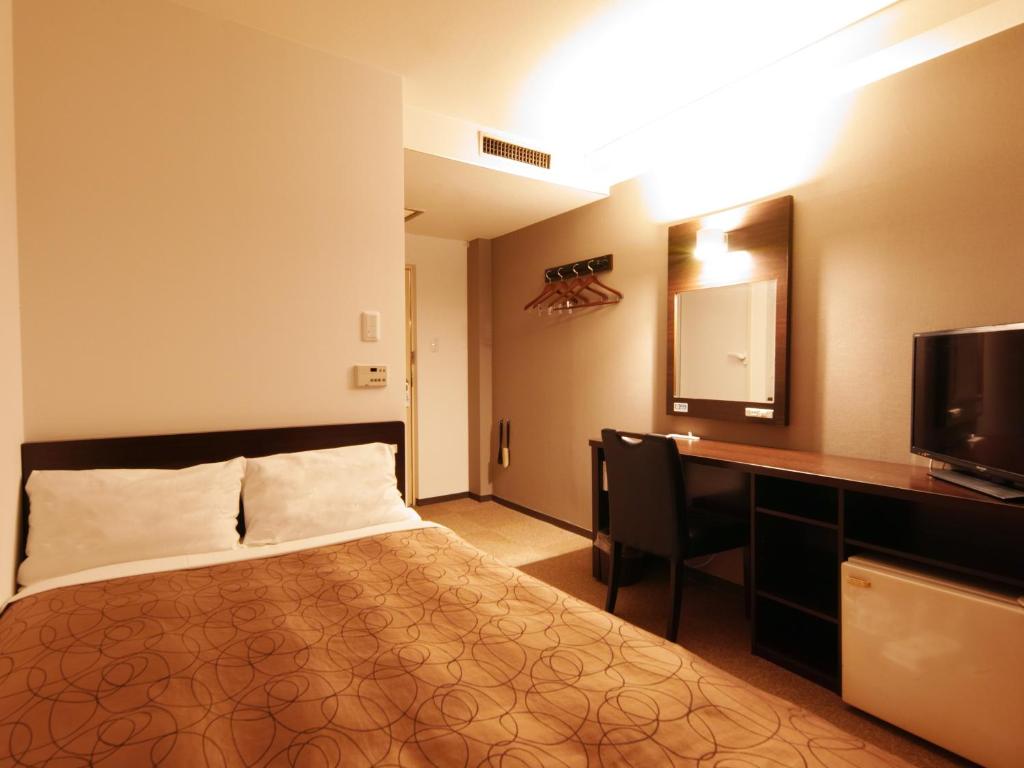 熊本熊本绿色酒店的酒店客房配有一张床、一张书桌和一台电视。