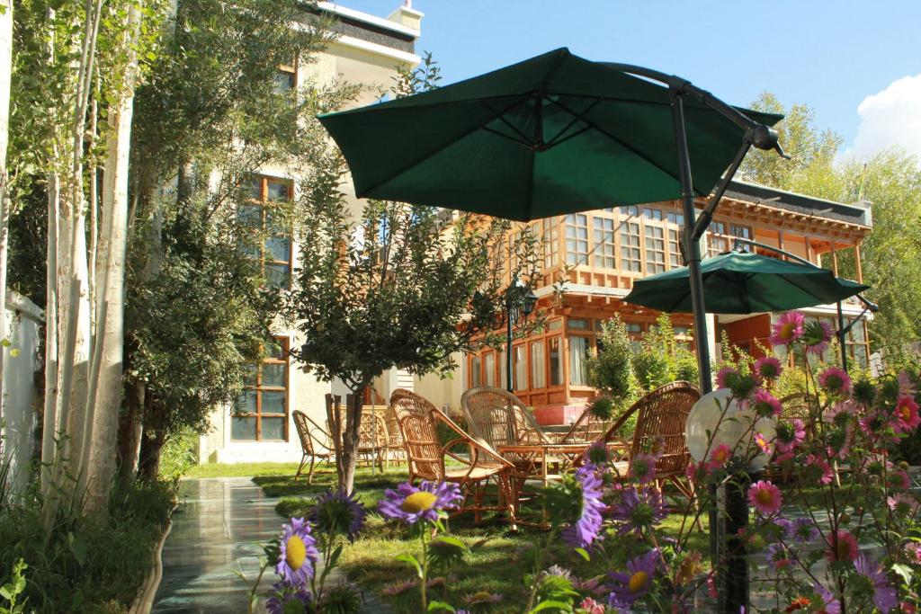 列城拉达克格林斯酒店的庭院设有椅子和遮阳伞,鲜花盛开