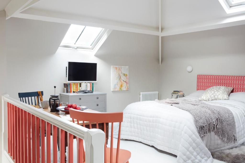 托特尼斯Stunning studio cntrl Totnes with parking的一间卧室配有一张床、一张书桌和一台电视。