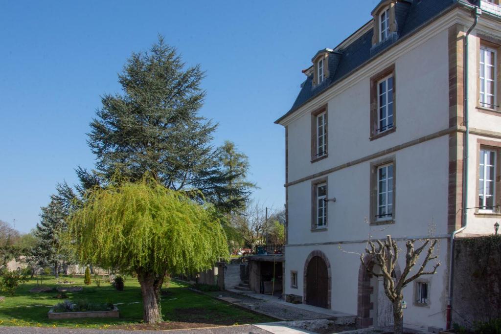 Réchicourt-le-ChâteauManoir Le Refuge的一座白色的老建筑,旁边是树