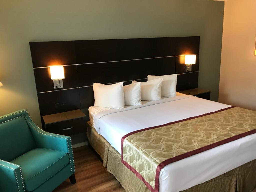 圣路易斯-奥比斯保Olive Tree Inn & Suites的配有一张床和一把椅子的酒店客房