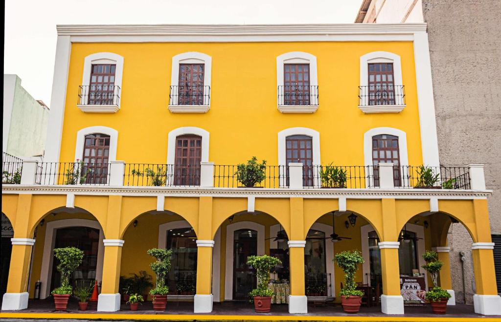 比亚埃尔莫萨马丹比亚埃尔莫萨贝斯特韦斯特酒店的黄色建筑,设有阳台和盆栽植物