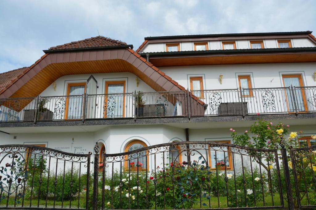 延纳斯多夫Pension Restaurant Rosenberg的带阳台和围栏的白色房屋