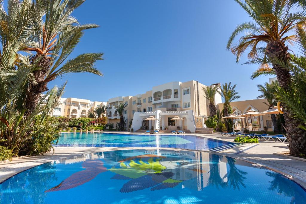 哈马马特Le Corail Appart'Hotel Yasmine Hammamet的酒店前方的棕榈树游泳池