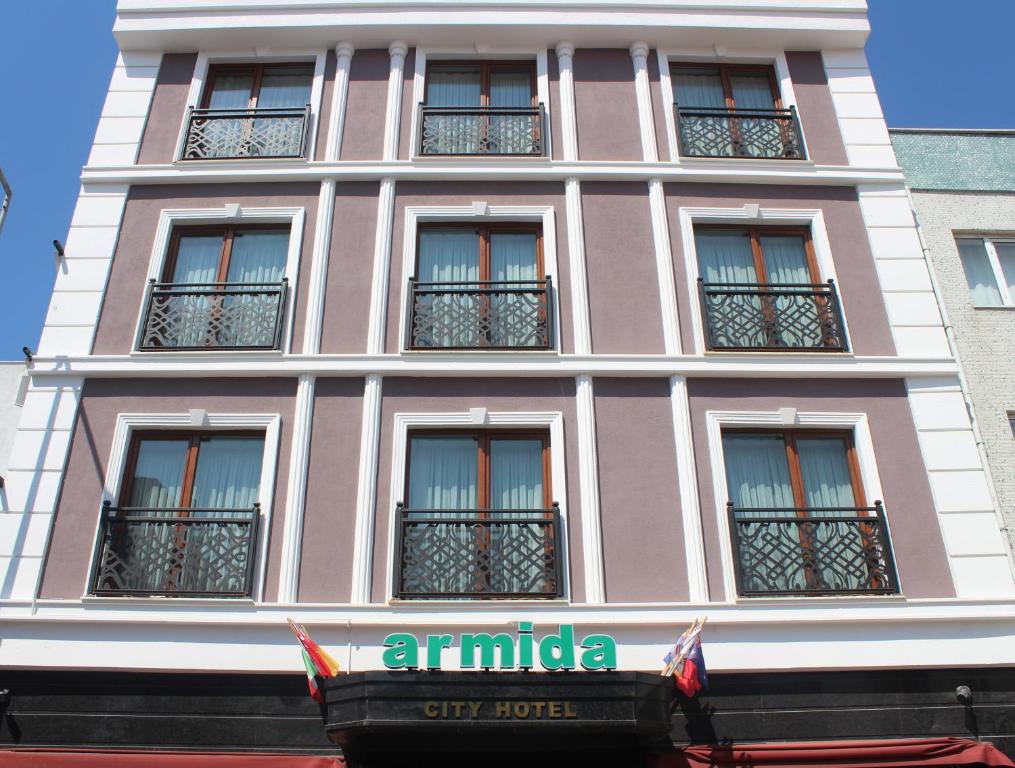 恰纳卡莱Armida City Hotel的粉红色的建筑,有窗户和标志