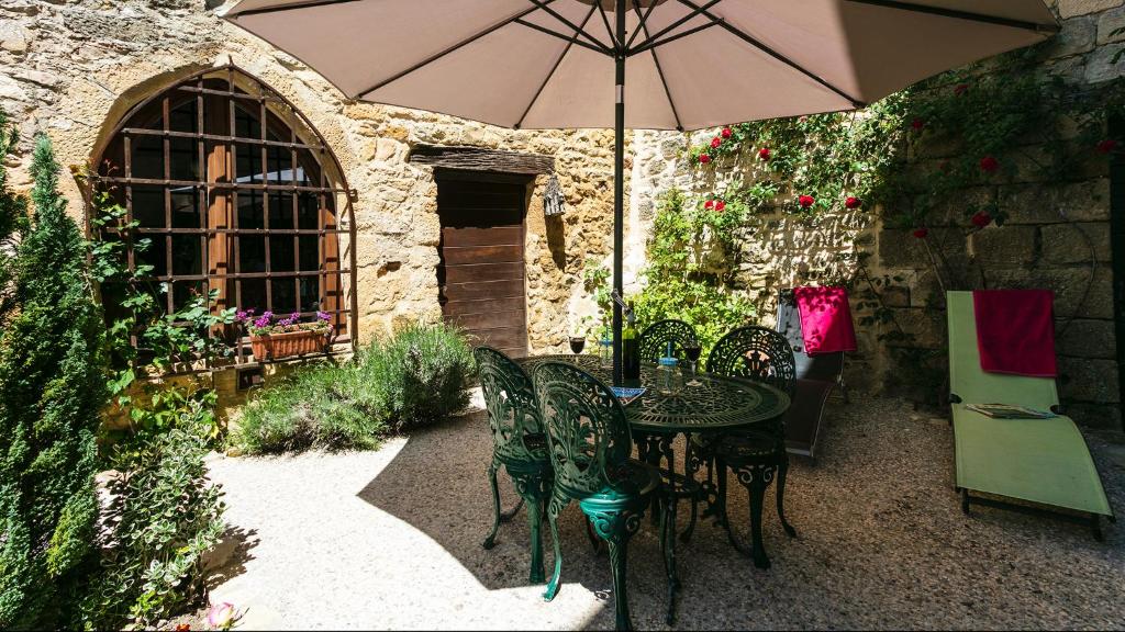贝纳克和卡泽纳克Au coeur de Beynac, une maison de caractère avec jardin terrasse的天井配有桌椅和遮阳伞