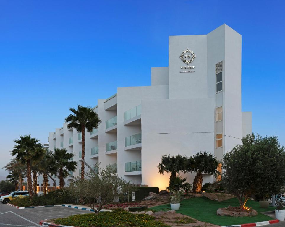 埃拉特Herbert Samuel The Reef Eilat的一座酒店大楼前面有棕榈树