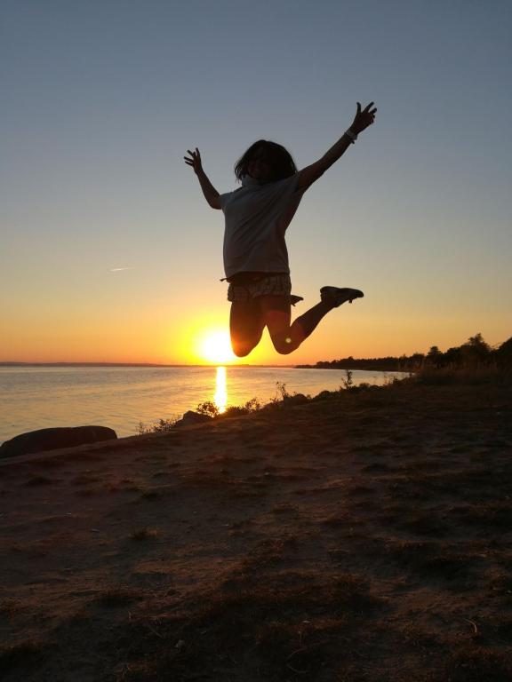 查普伊Przyczepa kemping Chałupy 3 Półwysep Hel的日落时在海滩上跳跃的人