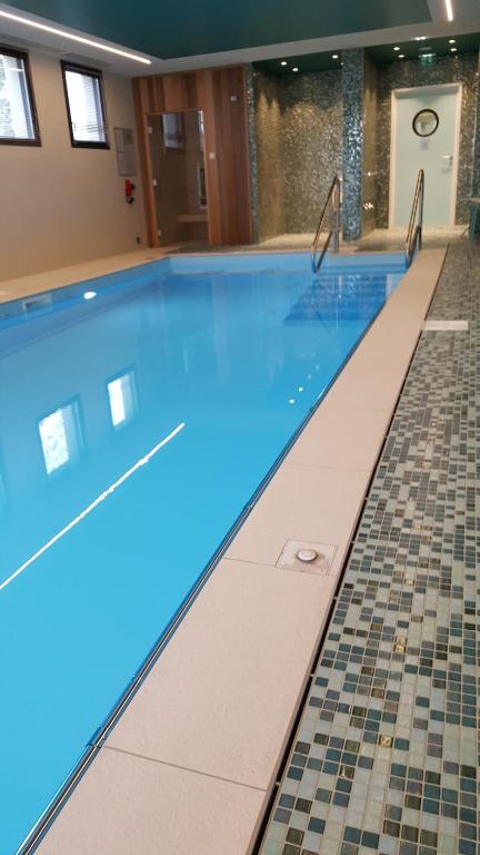 凯恩Domitys - Les Robes d'Airain的蓝色海水游泳池,铺有瓷砖地板