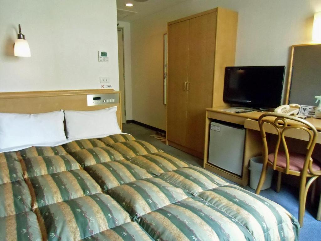 大阪Hotel Oaks Early-Bird Osaka Morinomiya/ Vacation STAY 28691的酒店客房配有一张床、一张书桌和一台电视。