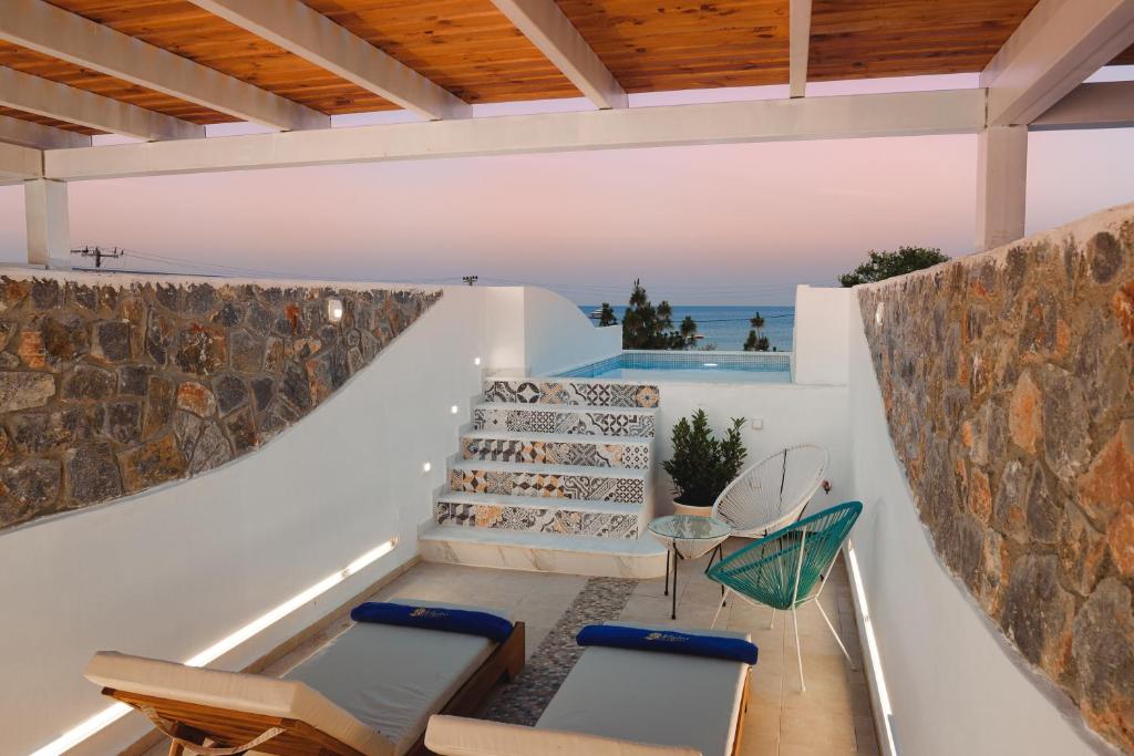 法里拉基Mylos Luxury Escape的一个带椅子和石墙的户外庭院