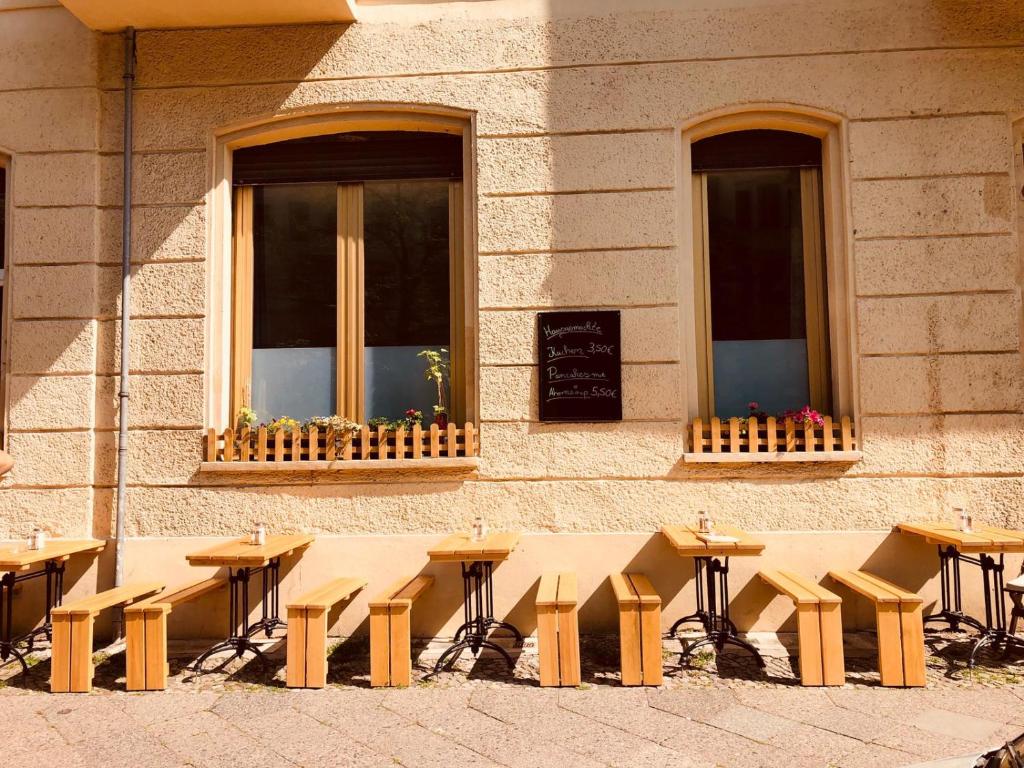 柏林Pension Kaffeefreunde的一组桌子和长凳在建筑物前