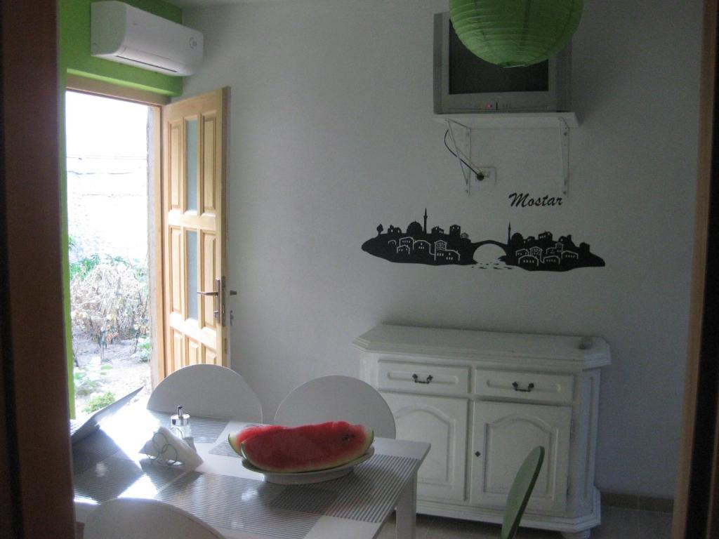 莫斯塔尔博霍青年旅馆的厨房配有一张桌子,上面放着一碗西瓜