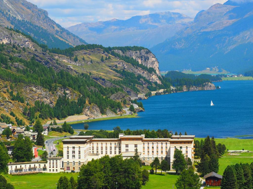 马洛亚Maloja Palace Residence Engadin-St Moritz CO2-Neutral的水体旁小山上的大建筑