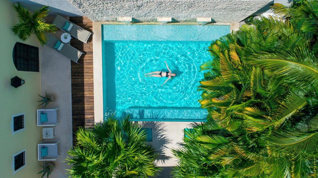 梅里达外交官精品酒店的在建筑物旁边的游泳池游泳的人